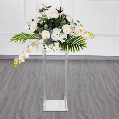 Elegant floral arrangement in a modern clear vase on a sleek pedestal.