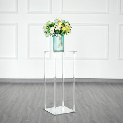Acrylic plant stand with a vase of flowers on a gray floor.