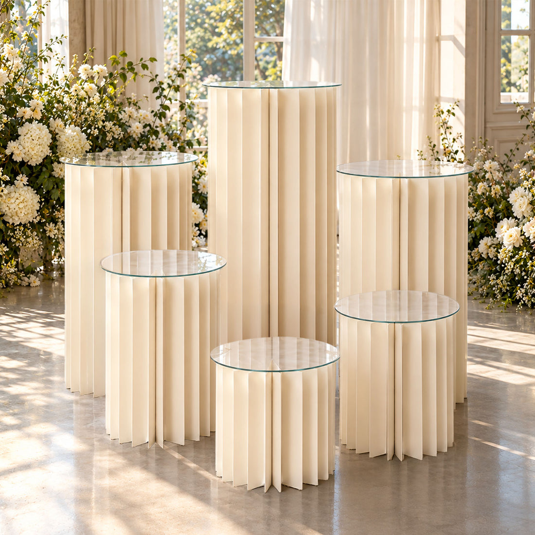 Elegant cream fluted pedestal tables with glass tops in floral event decor