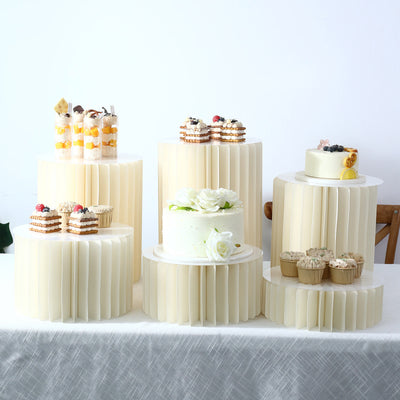 Elegant dessert table with cakes, cupcakes, and fruit parfaits on cream pedestals