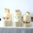 Elegant dessert table with cakes, cupcakes, and fruit parfaits on cream pedestals