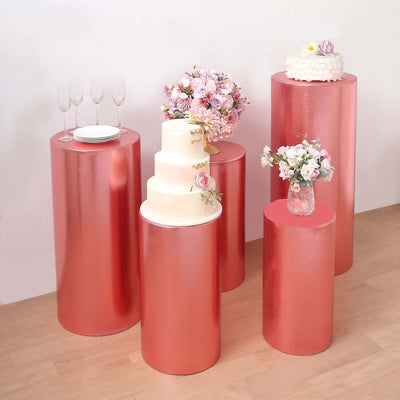 Set of pink metallic display pedestals with cake and floral arrangements.