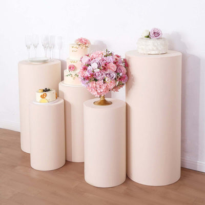Elegant display of wedding cakes and floral arrangements on pastel pedestals.