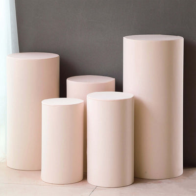 Set of five pastel pink cylindrical pedestals on a gray background.