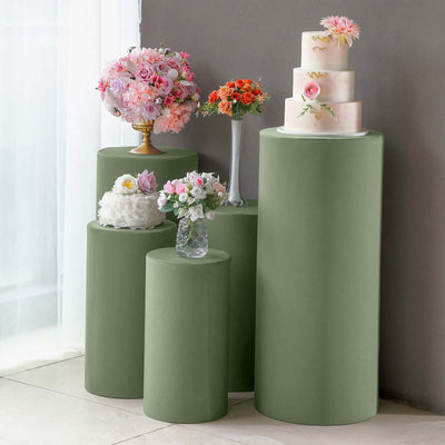 Green display pedestals with floral arrangements and a wedding cake.