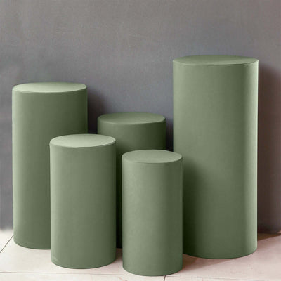 Set of five green cylindrical pedestals in varying heights against a gray background.