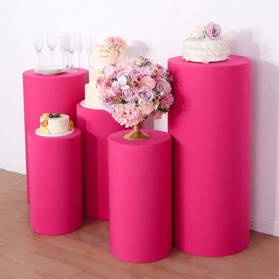 Pink display pedestals with cakes and floral arrangements for events.