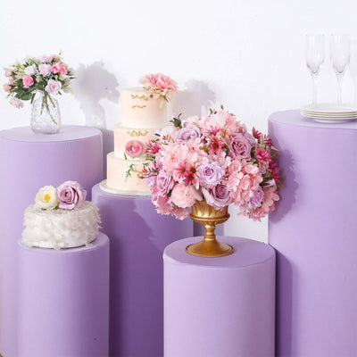 Decorative floral arrangement and cakes on purple pedestals for event styling.