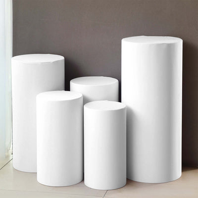 White cylindrical display pedestals of varying heights against a neutral background.