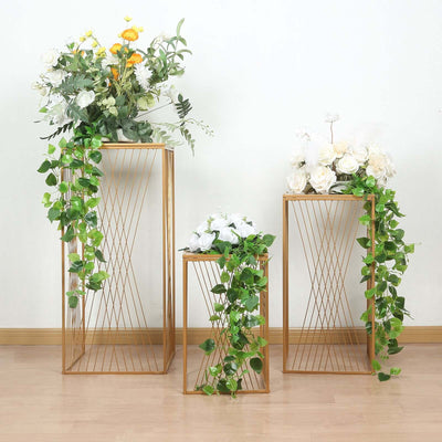Gold wire plant stands with greenery and flowers, perfect for home decor.