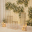 Elegant gold display stands with floral backdrop and candles for event decor.
