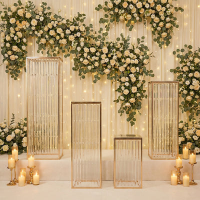 Elegant gold and glass display pedestals with floral backdrop and candles.