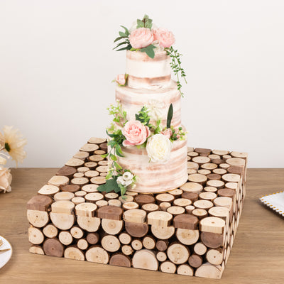 Three-tier wedding cake with pink flowers on a rustic wood slice stand.