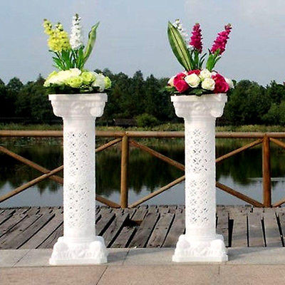 White decorative flower pillars with vibrant floral arrangements.