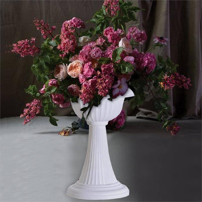 White pedestal vase with vibrant pink and purple flowers.