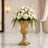 Elegant white floral arrangement in a gold pedestal vase in a luxury interior