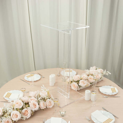 Clear acrylic display riser on a table set with pink roses and elegant dinnerware.