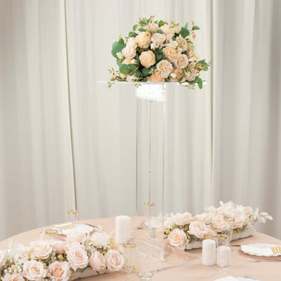Elegant floral centerpiece arrangement on a clear pedestal with soft roses.