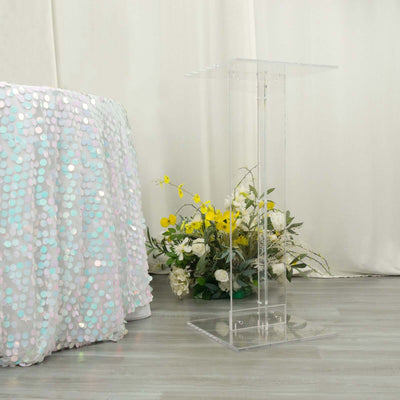 Acrylic podium next to a sequin tablecloth and floral arrangement.