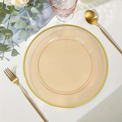 Elegant pink dinner plate with gold rim, set on a table with cutlery and glassware.