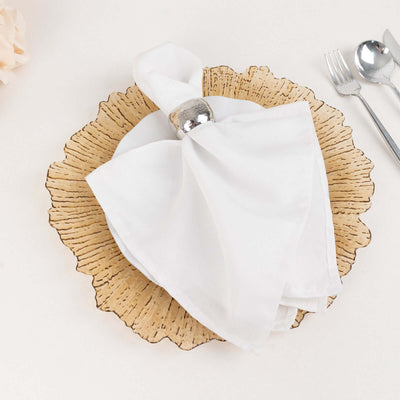 Elegant white napkin on a decorative plate with silver napkin ring.