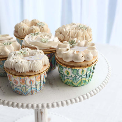 Decorative cupcakes on a cake stand with intricate wrappers.