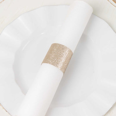 White napkin with gold glitter ring on a white plate.