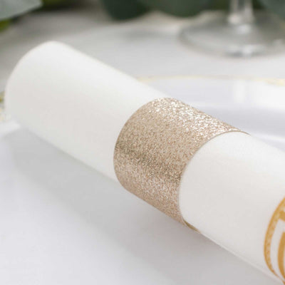 Gold glitter napkin ring on a white napkin.