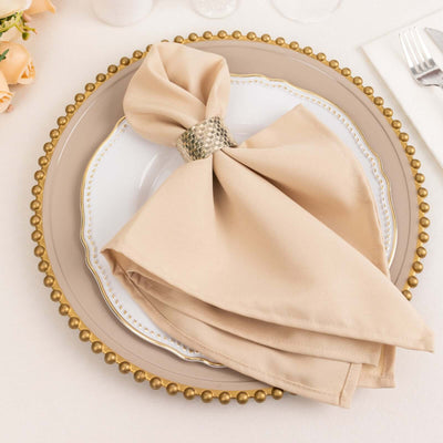 Elegant beige napkin on a decorative plate with a silver napkin ring.
