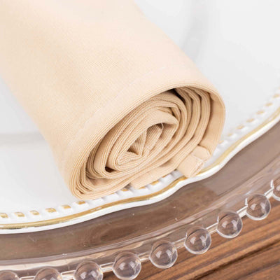 Rolled beige linen napkin on a decorative plate.