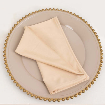 Beige cloth napkin neatly folded on a decorative plate.