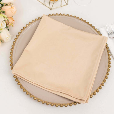 Beige napkin folded neatly on a decorative plate with a gold rim.