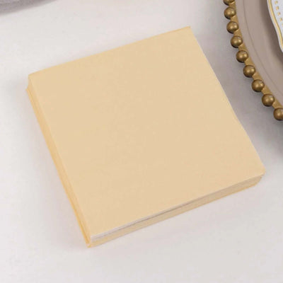 Yellow napkin stacked on a table with decorative plate.