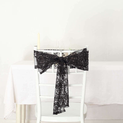 Black lace chair sash tied in a bow on a white chair at a dining table.
