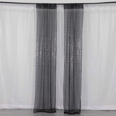 Black sheer curtains with glitter detail hanging in a studio setting.