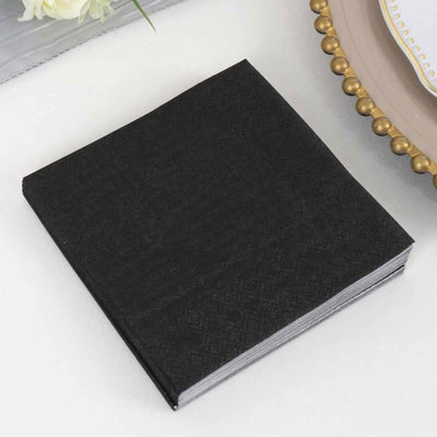 Black paper napkins stacked on a table.