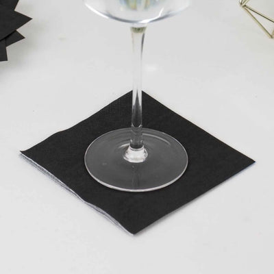 Black beverage coaster under a glass on a white surface.