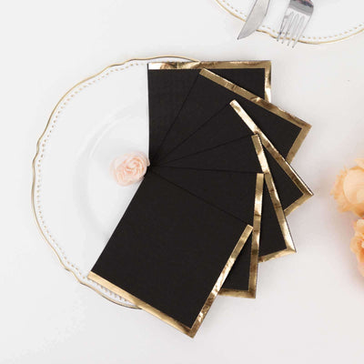 Black envelopes with gold foil trim arranged on a decorative plate.