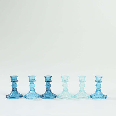 Blue glass candlesticks in varying shades arranged in a row.