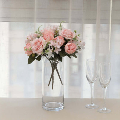 Pink rose and white flower bouquet in a glass vase with champagne flutes.