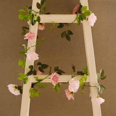 Decorative ladder adorned with pink rose flowers and greenery.