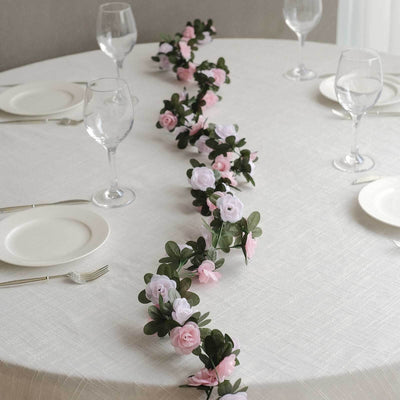 Floral table runner with pink and white roses on a dining table.