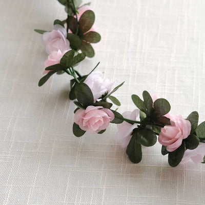 Floral crown with pink and white roses and green leaves on a textured background.