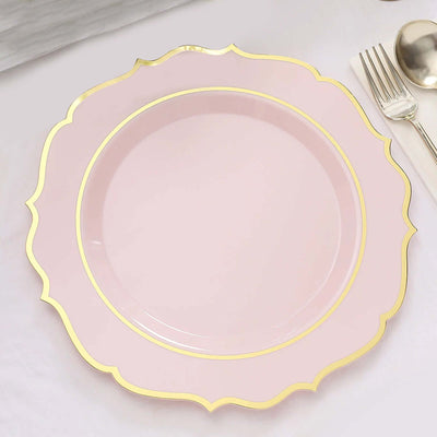 Pink decorative plate with a gold rim on a plain background.