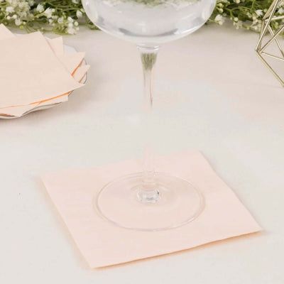 Pink napkin under a glass on a table with decorative elements.