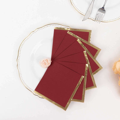 Elegant burgundy envelopes with gold trim on a decorative plate.