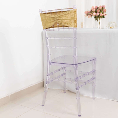 Clear ghost chair with a gold accent backrest, set against a neutral background.