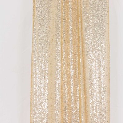 Gold sequined fabric draped elegantly on a white backdrop.