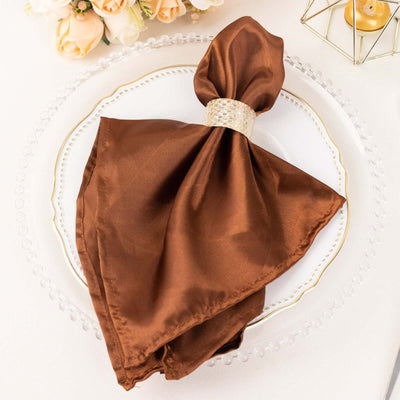Brown satin napkin with a decorative ring on a plate.