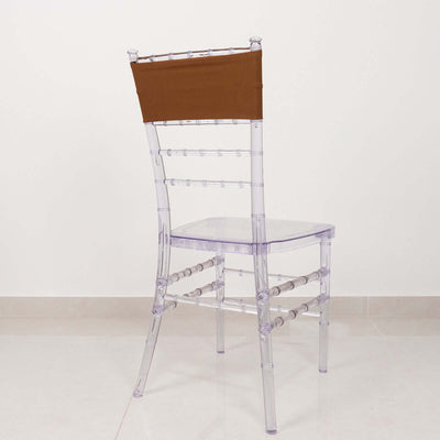 Transparent chiavari chair with brown cover on a plain backdrop.